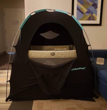 a reviewer photo of the SlumberPod with the front zip door open showing a play peen inside 