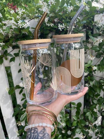 model holding two tumblers with a lid and straws