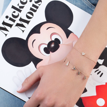 a model wearing the mickey and friends charm bracelet and a thin bracelet with a mickey icon on it