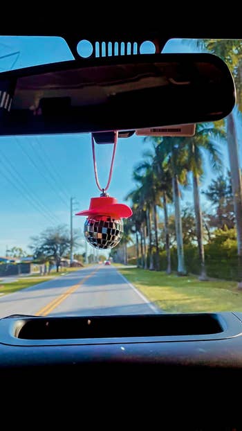 the cowgirl disco ball hanging from the rearview mirror in a car