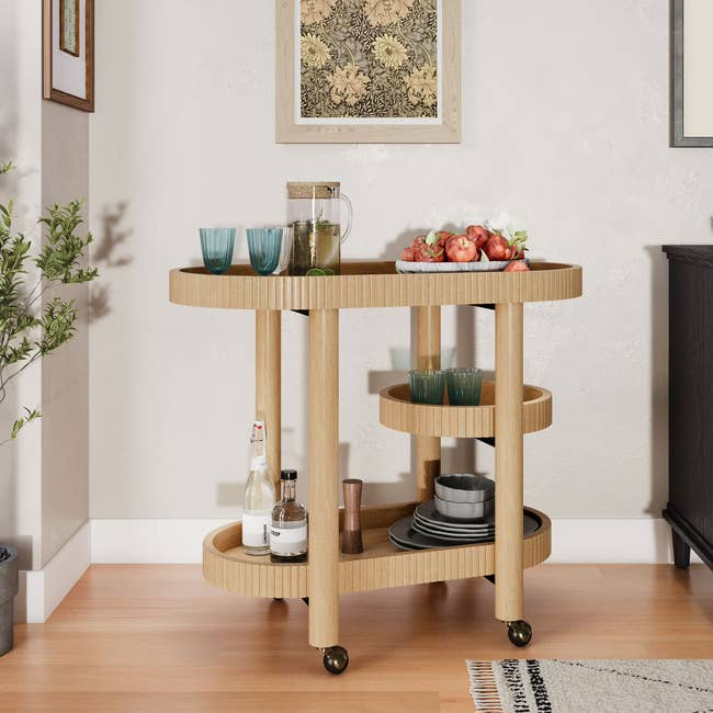 Stylish woody barroom cart with wheels, bottles, glasses, and a effect bowl, cleanable for serving drinks successful a modern location setting