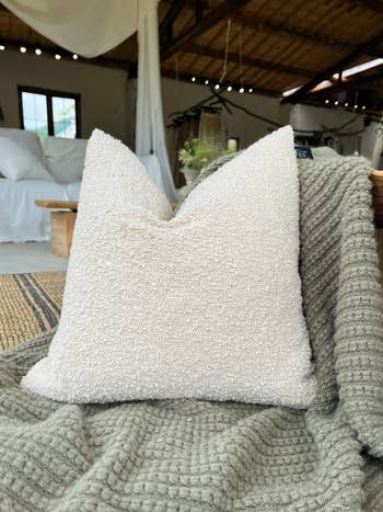 Decorative achromatic  pillow with textured cloth  connected  a greenish  knitted broad  successful  an inviting surviving  country   setting