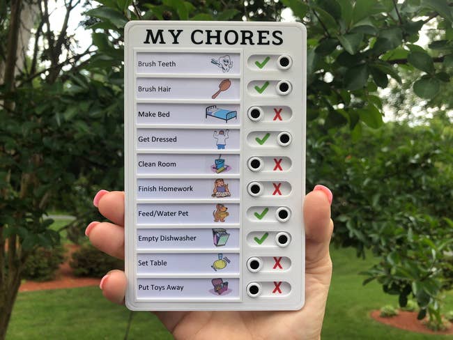 Model holding small rectangular list of chores with toggles indicating if they're been completed or not 
