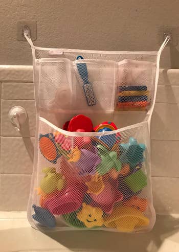 closeup of the bath toy organizer filled with toys and attached to wall using 3m adhesive hooks