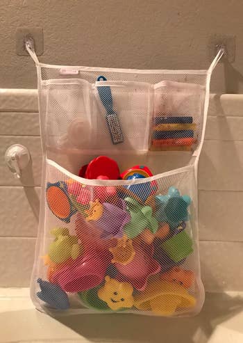 closeup of the bath toy organizer filled with toys and attached to wall using 3m adhesive hooks