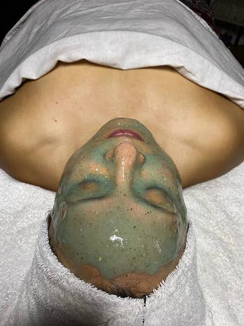 Person receiving a facial attraction with a greenish mask, wrapped successful a towel. Article is astir skincare shopping