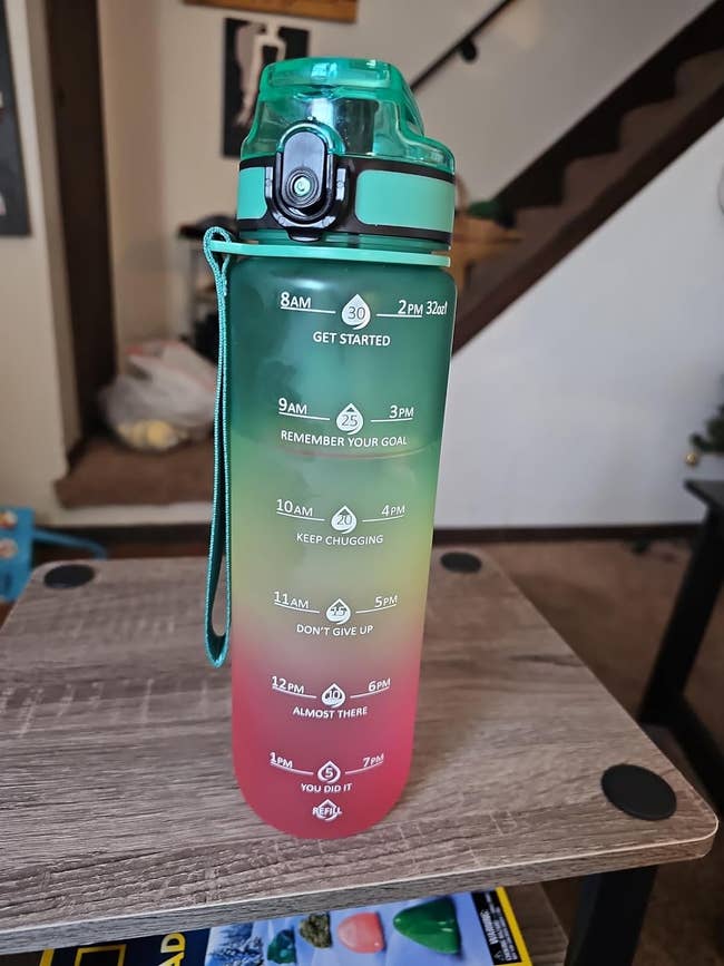 Motivational water bottle with time markers for drinking goals and encouraging phrases