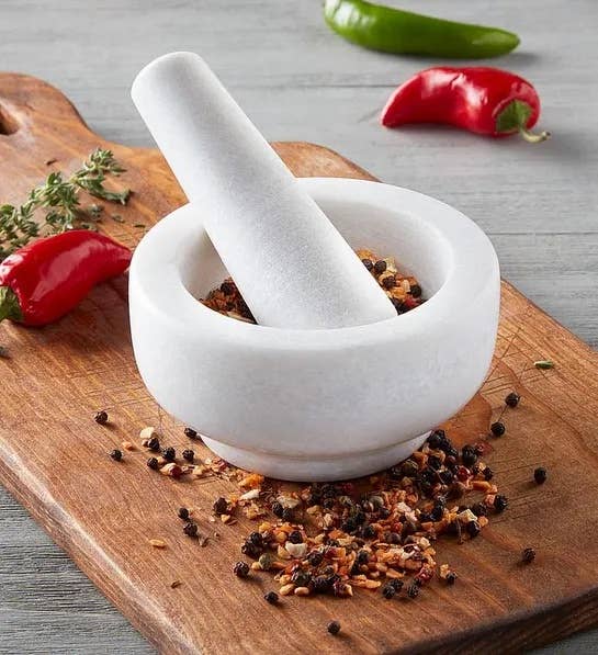 the white mortar and pestle filled with spices on a cutting board