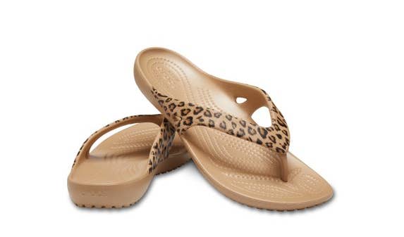 Pair of leopard people flip-flops with textured soles, positioned somewhat overlapping connected a neutral background