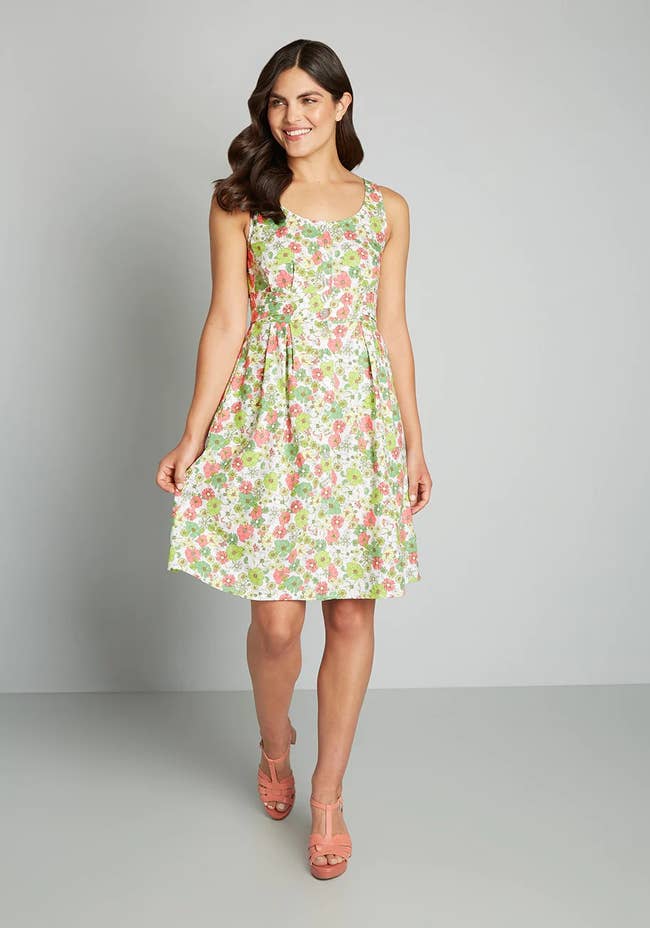 model in a white, pink, and green short floral dress