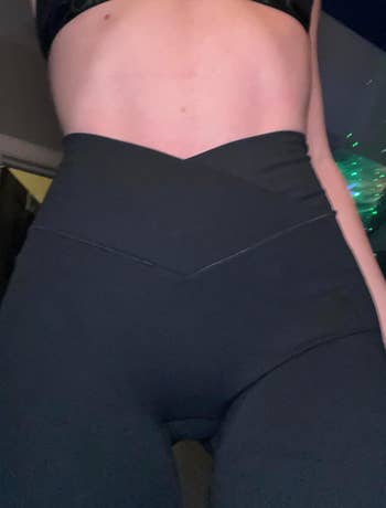 A close-up image showing a person wearing high-waisted, form-fitting leggings with a V-shaped waistband