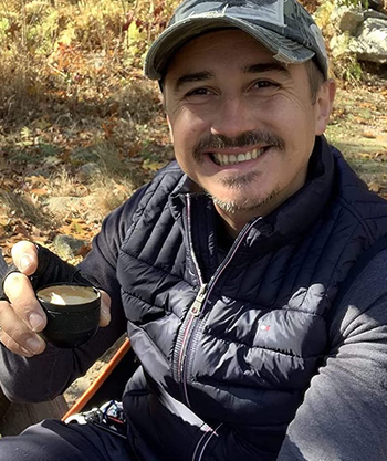 same reviewer holding a cup of espresso that was made using the portable espresso maker