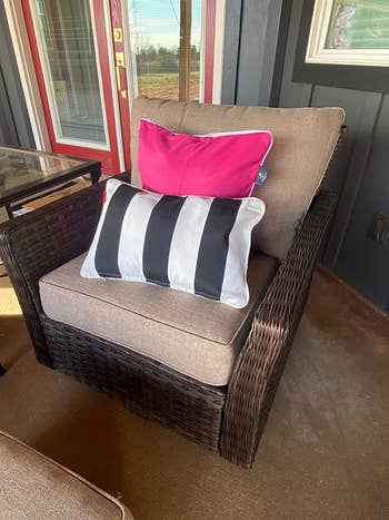 a reviewer's outdoor chair with a hot pink pillow and a striped pillow