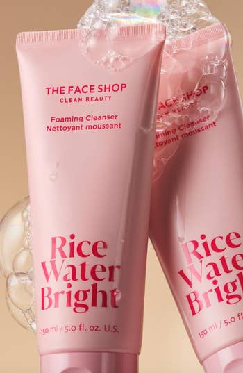 Two bottles of 'The Face Shop Rice Water Bright' foaming cleanser with bubbles