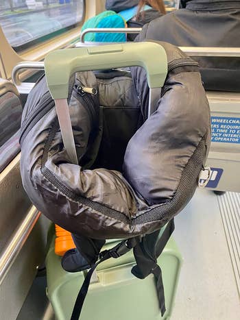 neck pillow stufed with clothes and looped on a suitcase handle