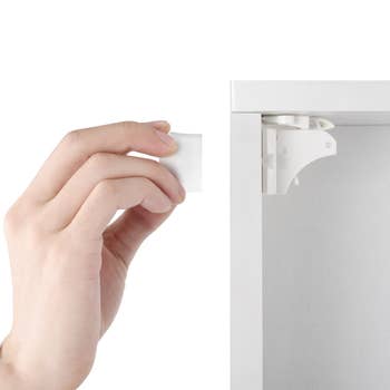 model's hand holding magnet outside of cabinet with the lock inside