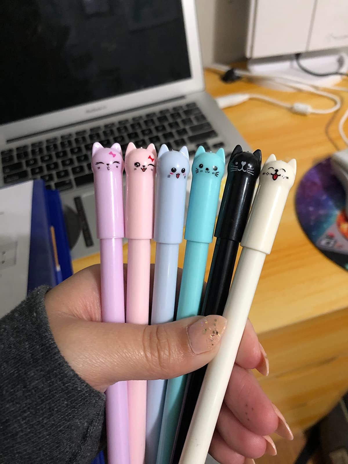 hand holding six of the colorful cat gel pens