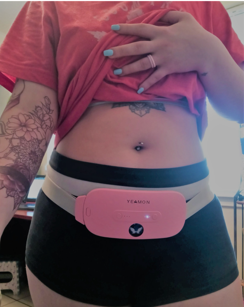 Reviewer wearing pink oval-shaped belted heating pad around their hips