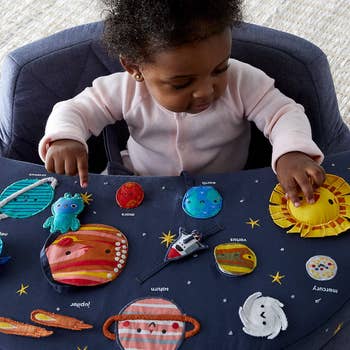 Baby successful a precocious seat interacting with a star system-themed cloth book