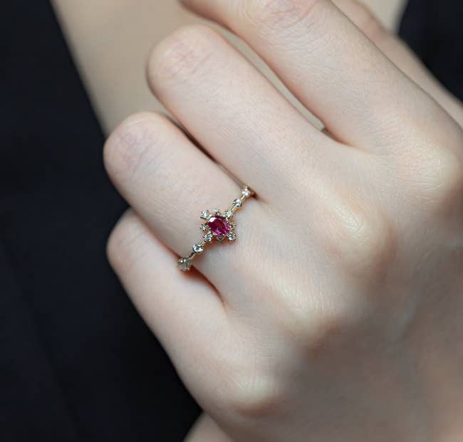 The red diamond ring with four tinier diamonds surrounding it and small diamonds down the band