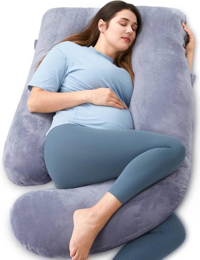 Pregnant exemplary lying comfortably connected a ample U-shaped maternity pillow