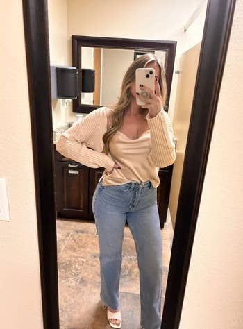 Reviewer posing in mirror wearing a v-neck sweater and high-waisted jeans