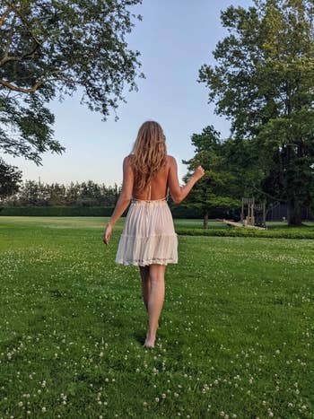 reviewer walking, showing off back of white halter dress