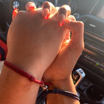 review image of couple's hands with bracelet charms clung together