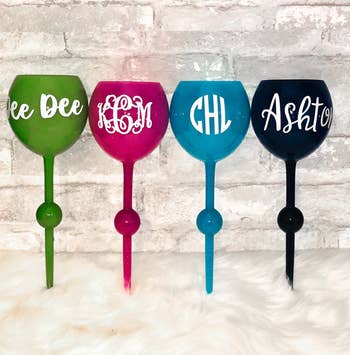 The wine glasses with monograms on them in green, pink, blue, and black