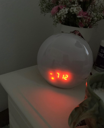 The circular alarm clock with the time stamp on it  on a reviewer's table