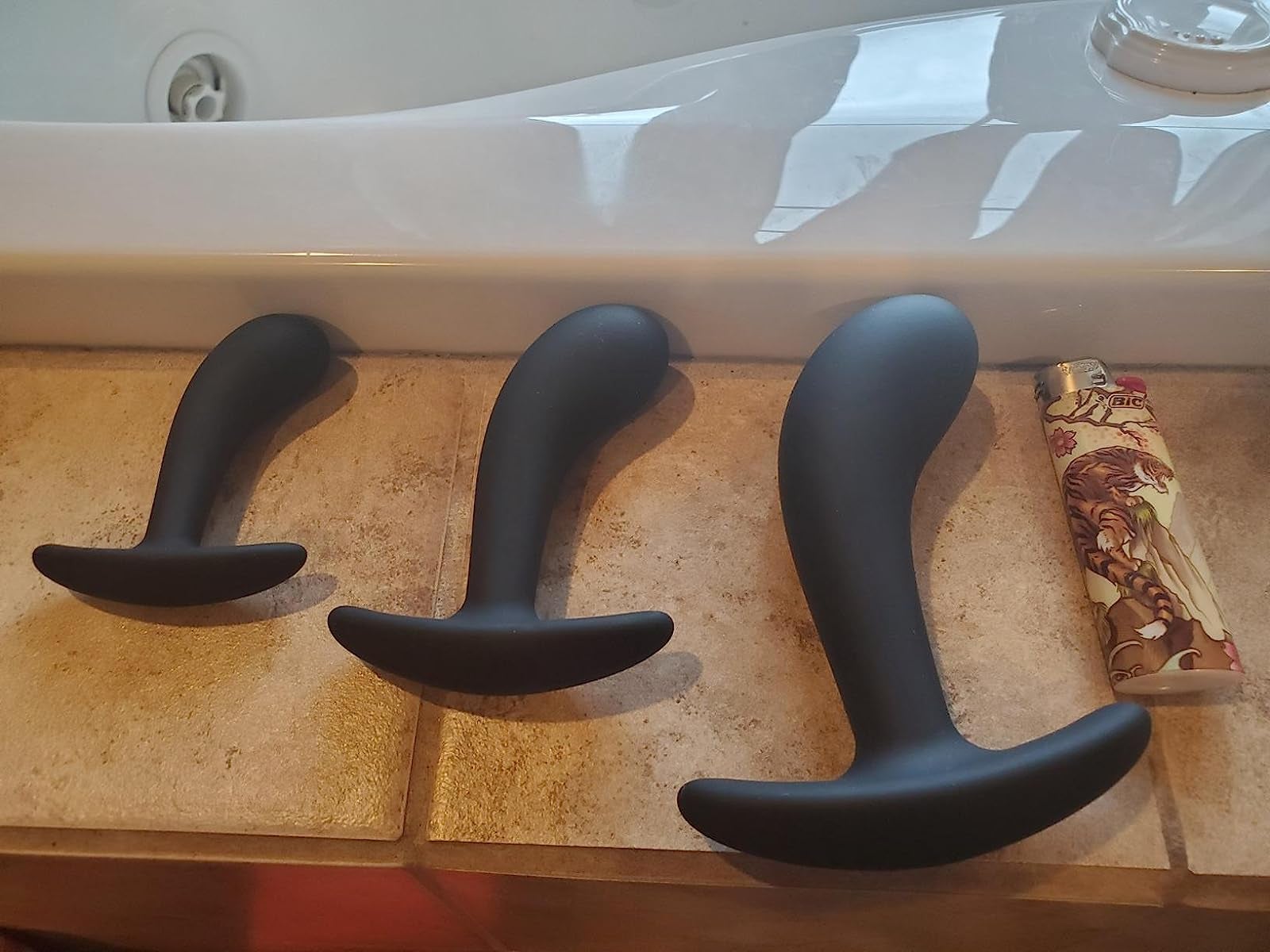 Three black plugs in different sizes next to lighter for comparison