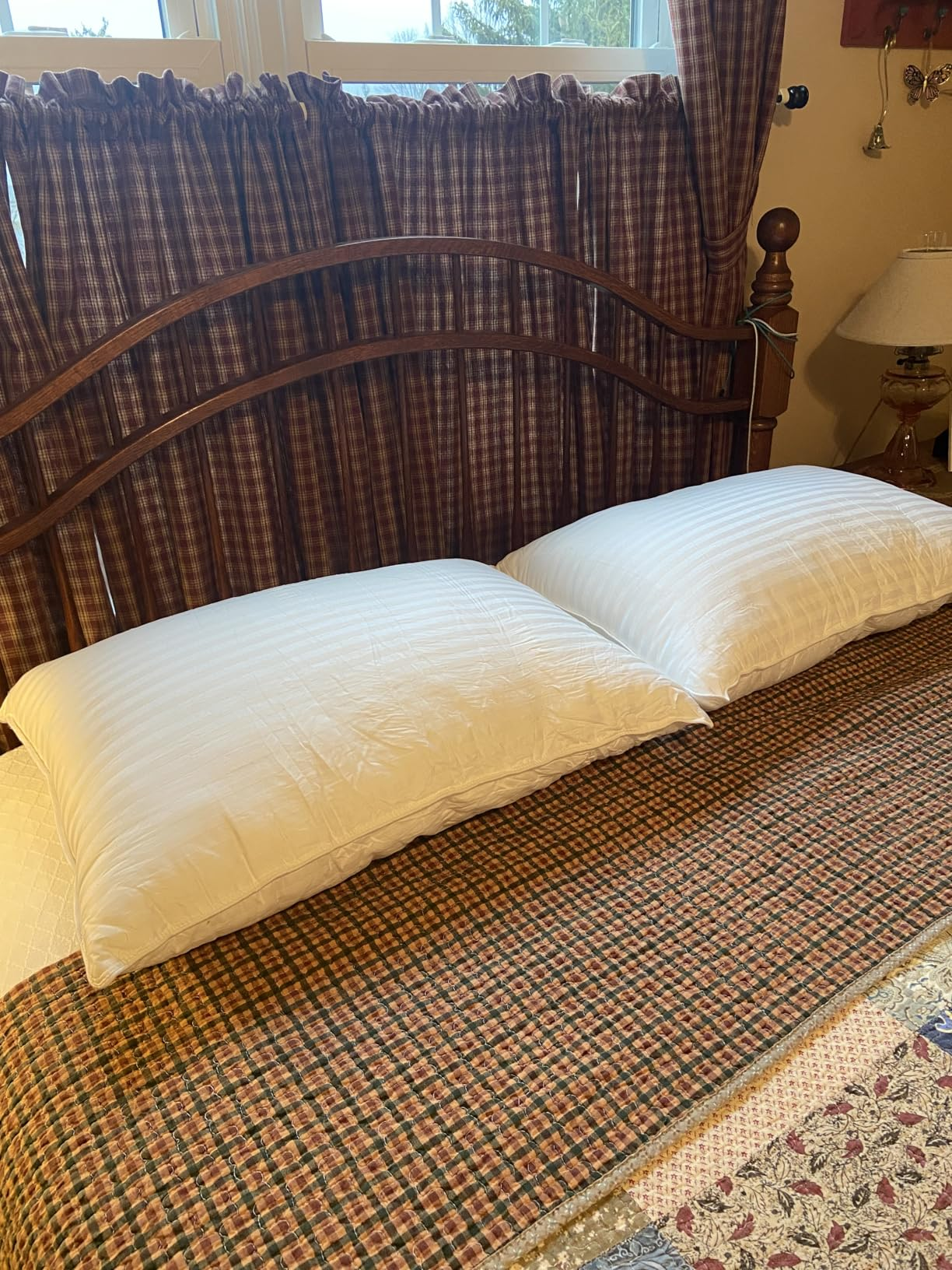 Two achromatic  pillows connected  a neatly made furniture  with plaid bedding and curtains, creating a cozy chamber  setting