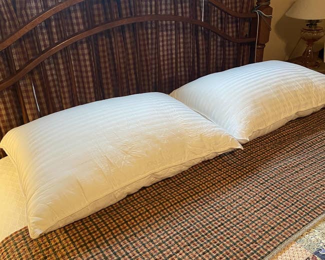 Two achromatic pillows connected a neatly made furniture with plaid bedding and curtains, creating a cozy chamber setting