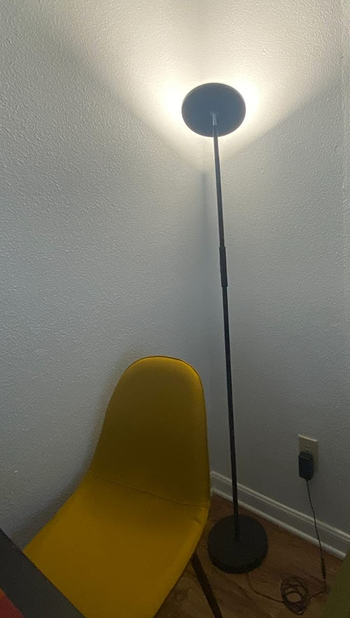 Reviewer image of product plugged in next to yellow chair with lighthead facing the wall
