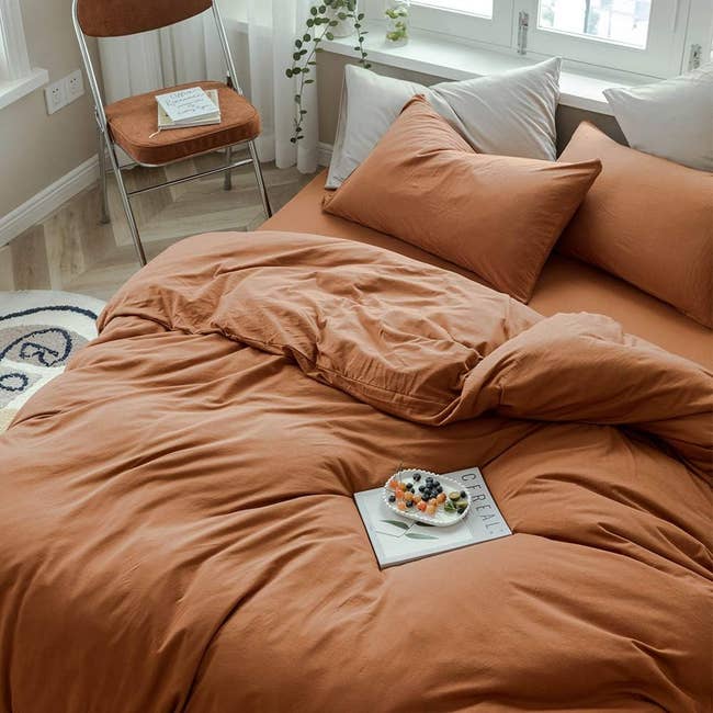 the duvet set in a muted orange color on a bed 