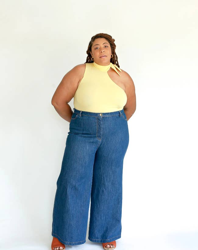 model in yellow sleeveless tie-collar bodysuit and wide leg jeans