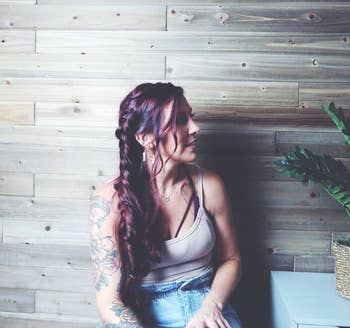 Reviewer sitting in front of wooden wall with red shiny smooth hair