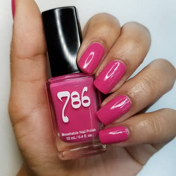 A hand holding a pink 786 nail polish