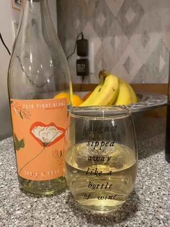 the wine glass filled with wine next to a wine bottle