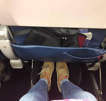 a reviewer using the footrest on an airplane 