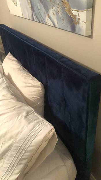 a close up of a reviewer's navy bed frame showing the velvet texture