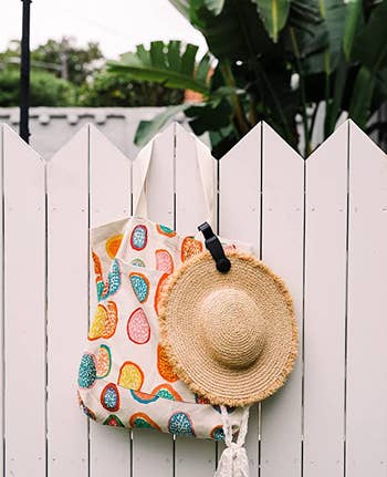 the magnetic hat clip holding a wide brim straw hat onto a tote bag