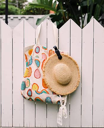 the magnetic hat clip holding a wide brim straw hat onto a tote bag