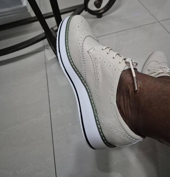 Person wearing stylish level oxford shoes with elaborate stitching