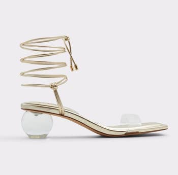 a gold tone sandal with a clear spherical heel and ankle laces 