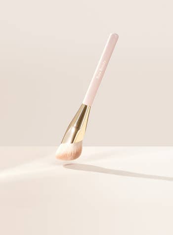 Makeup brush with a sleek handle and fluffy bristles, positioned elegantly. Perfect for applying powders or foundations, ideal for beauty enthusiasts