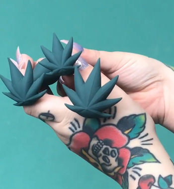 Model holding green butt plugs to display leaf-shaped base