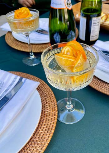 A cocktail with an orange slice garnish on an outdoor table, suggesting a dining shopping experience