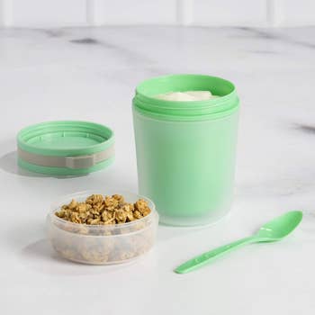 Reusable snack container with lid open with granola in it