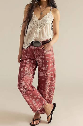 Person wearing a lace-trimmed camisole, patterned wide-leg pants, sandals, and a necklace, posing for a fashion-related article